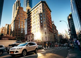 Home A bustling New York City street with towering buildings at golden hour, capturing urban life.