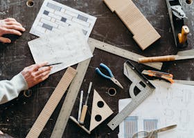 Home Tools and hands on a workbench during a woodworking project featuring plans and equipment.