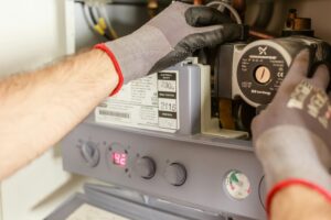 Home Close-up of hands adjusting a boiler system with precise instrumentation, showing maintenance work.